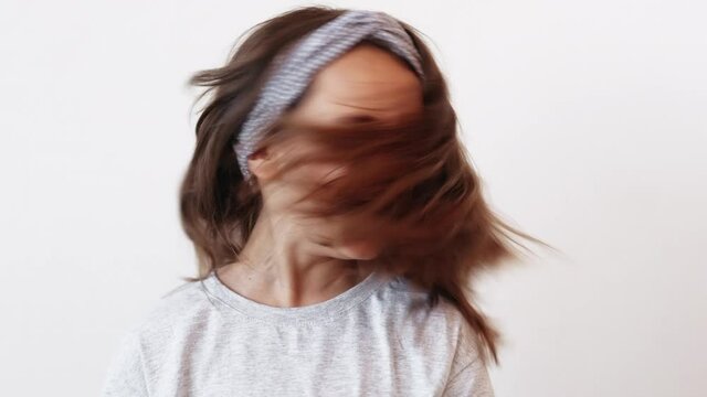 Joyful kid. Carefree childhood. Holiday inspiration. Excited happy impressed small girl having fun enjoying playing with soft flying hair turning head laughing isolated on light neutral background.