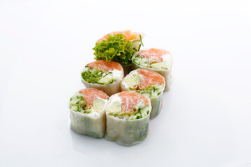 Spring rolls with raw salmon and fresh vegetables, isolated on white background, with a copy-space. Sushi rolls in rice paper, a packshot photo for an oriental restaurant menu. Asian cuisine delicacy.