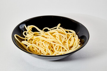 Long spaghetti in a black plate on a white background