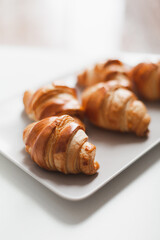 Fresh croissants on a gray rectangular plate on a white background
