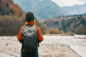 happy woman in autumn forest in the mountains outdoors with a backpack on her back travel tourism
