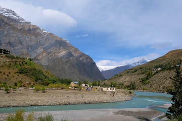 A cozy little village on the banks of a turquoise river in the mountains of the Himalayas on a clear autumn day