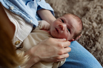 Little newborn baby boy in mom's arms at home
