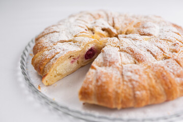 Pie with cottage cheese and berry jam sprinkled with powdered sugar on a white plate