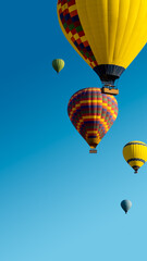 Fototapeta premium Hot Air Balloons ride for promotion of your travel agency or tour to Cappadocia, vertical landscape. Ballooning trip at clear blue sky background with copy space for text, bottom up view.