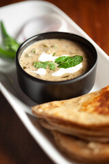 Close-up of Methi, matar malai  with   white curry. Served with paratha or roti. A popular, delicious Indian recipe in black bowl.