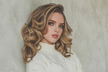 Portrait of perfect woman with blonde curly hair on gray background