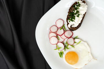 Healthy breakfast, top view. Fried eggs, greens, radishes, baguette with cream cheese.
