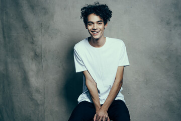 happy curly guy in a t-shirt gesturing with his hands on a fabric background in a studio photoshoot model