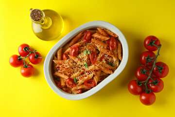 Tray with pasta with tomato sauce and ingredients on yellow background, top view
