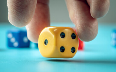 The hand is throwing yellow dice on the blue table. Concept of a casino and a lucky chance to win