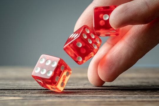 The hand is throwing red dices on the wooden table. Concept of a casino and a lucky chance to win