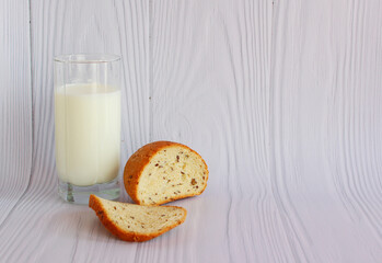 Glass of fresh milk with sliced bread isolated on wood background