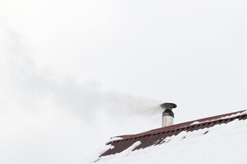 Naklejka na ściany i meble The chimney smokes on the roof of the house