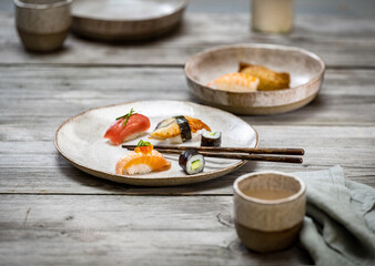 Fototapeta na wymiar Food photo with sushi maki and nigiri on light ceramic plate arranged on a rough gray wooden table.