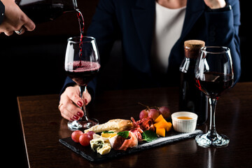 Woman holding glass of red wine on blurred background