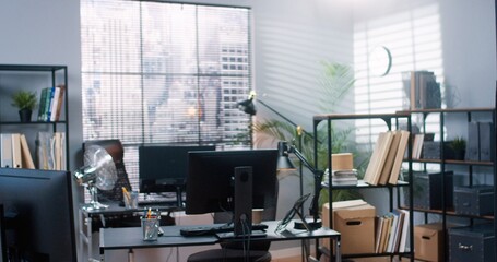 Portrait of young pretty Caucasian woman employee in medical mask in cabinet packing stuff from work desk in carton box. People lost job. Mixed-races workers packing and leaving office fired from work