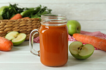 Jar of apple - carrot juice and ingredients on white wooden background