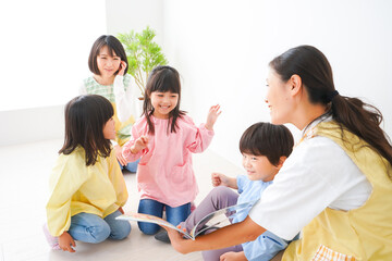 Fototapeta premium 絵本の読み聞かせをする保育士と子どもたち