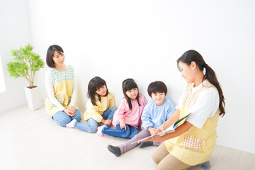 絵本の読み聞かせをする保育士と子どもたち