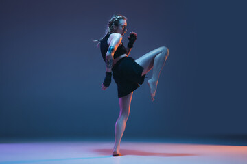 Caucasian female MMA fighter training isolated on blue background in neon light