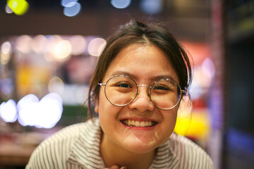 Asian girl who wear glasses is smiling with night bouquet background