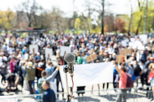 Protest or public demonstration, focus on microphone, blurred crowd of people in the background