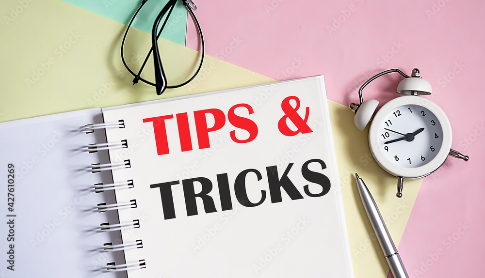 Poster tips and tricks on the notebook with pen,alarm clock on pink background