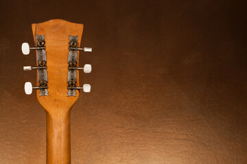 Back of the acoustic guitar head on a blurred background.