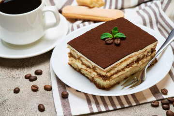 Portion of Traditional Italian Tiramisu dessert and savoiardi cookies on grey concrete background