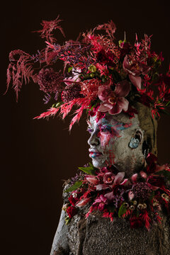 Portrait of a girl smeared with clay in a cemented dress. On the girl's head is a portrait of fresh flowers