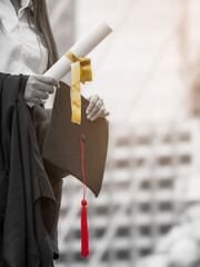 Vertical image, close up graduate holding certificate and grads cap.