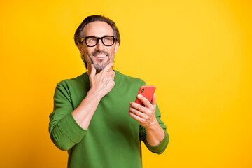 Photo of minded man hold telephone finger chin look up empty space wear glasses green pullover...