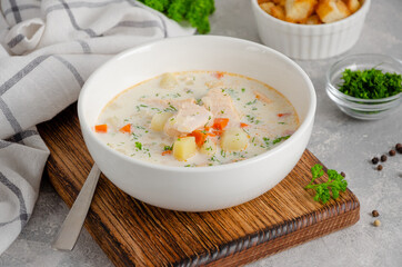 Salmon soup with cream, potatoes, carrots, herb and croutons in a bowl on a gray concrete background. Copy space.