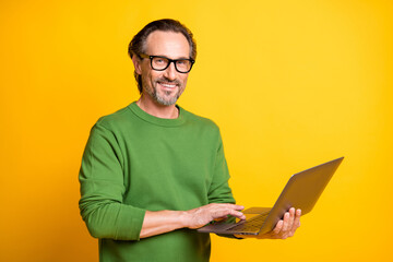 Photo of man hold netbook hand touch pad wear eyewear green sweater isolated yellow color background