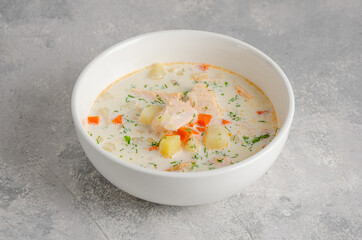 Salmon soup with cream, potatoes, carrots, herb and croutons in a bowl on a gray concrete background. Copy space.