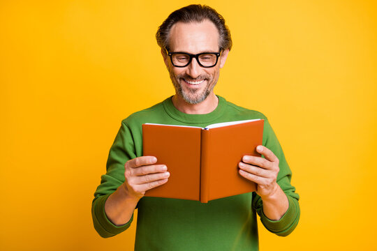 Photo of man hold textbook read beaming shiny smile enjoy wear spectacles green pullover isolated yellow color background
