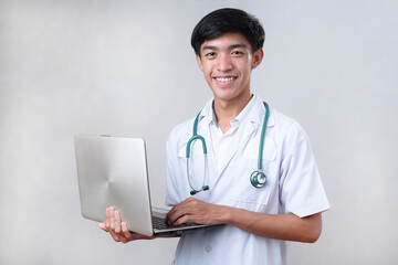 Smiling Young Asian Male doctor standing and working on a laptop