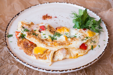 Omelet with vegetables, ham and cheese. Breakfast at the restaurant. Egg dish.