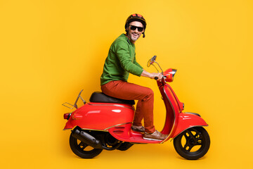 Photo of man drive bike wear helmet sunglass green pullover pants footwear isolated yellow color background