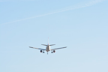 Passenger airplane in flight from behind with blue sky