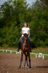 A girl rider trains riding a horse on a spring day.