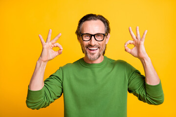 Photo of funny bristled guy show two okey signs wear eyewear green sweater isolated yellow color background