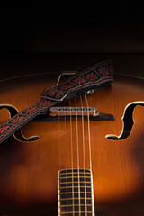 Acoustic guitar with bridge and strings on a black background.