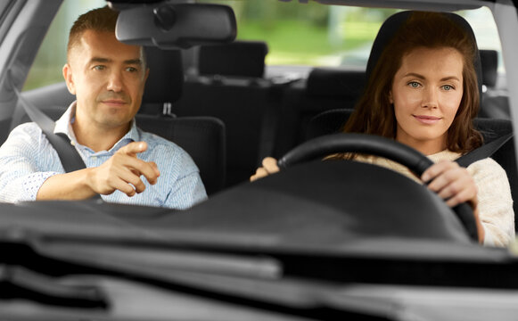 driver courses and people concept - car driving school instructor teaching young woman to drive