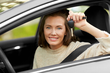 driving, safety and people concept - young woman or female driver sitting in car and showing key