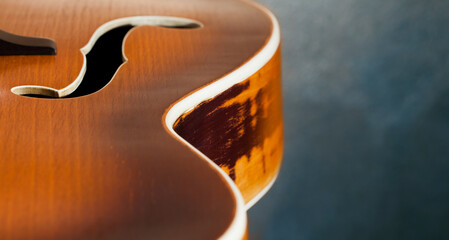 A fragment of the soundboard of an acoustic guitar on a blurred, blue background.