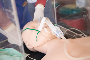 Closeup of hand putting nebulizer mask to manikin via plastic box. Demonstration of respiratory support for dyspnea, pneumonia, coronavirus infection patient concept. Selective focus