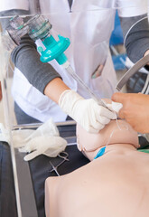 Closeup of hand wearing glove intubating endotracheal tube into manikin via plastic box. Resuscitation, acute respiratory failure, coronavirus infection concept. Soft focus