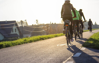 Młodzi ludzie jadą na rowerze w słoneczny dzień - obrazy, fototapety, plakaty